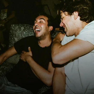 Gifts for brothers: two young men laughing and hugging on a sofa