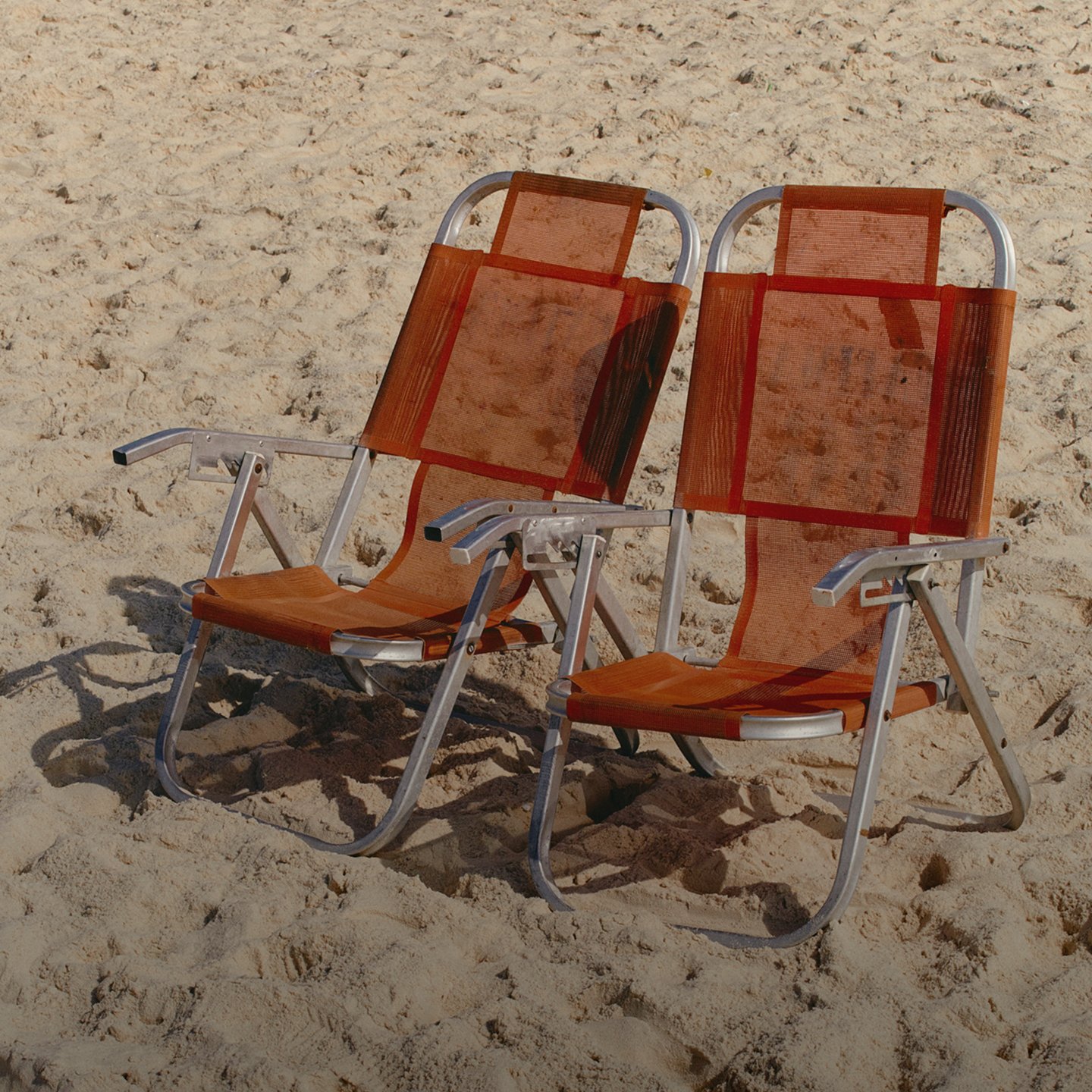 Two chairs next to each other on a beach