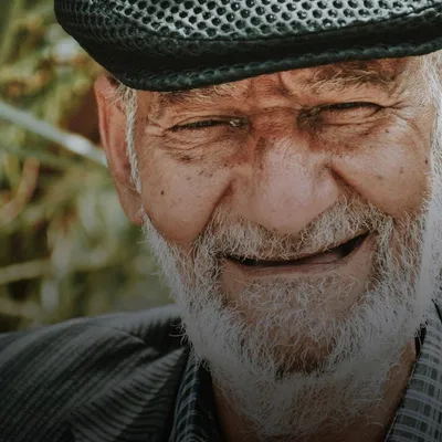 Gifts for grandpa: close-up of a smiling older man with a white beard and flat cap
