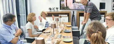A group of people sitting at a table prepared with plates and wine glasses