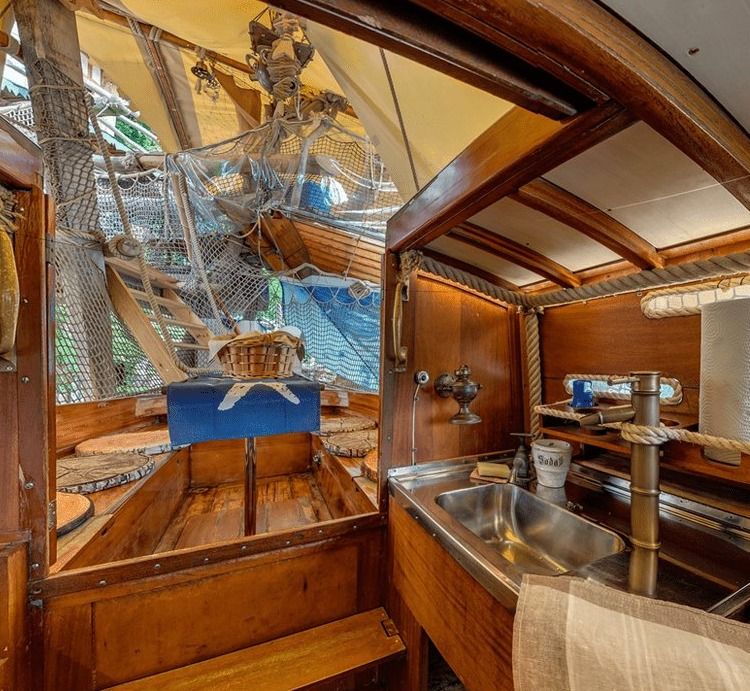 Small galley with stainless steel sink inside the wooden cabin of a sailboat treehouse