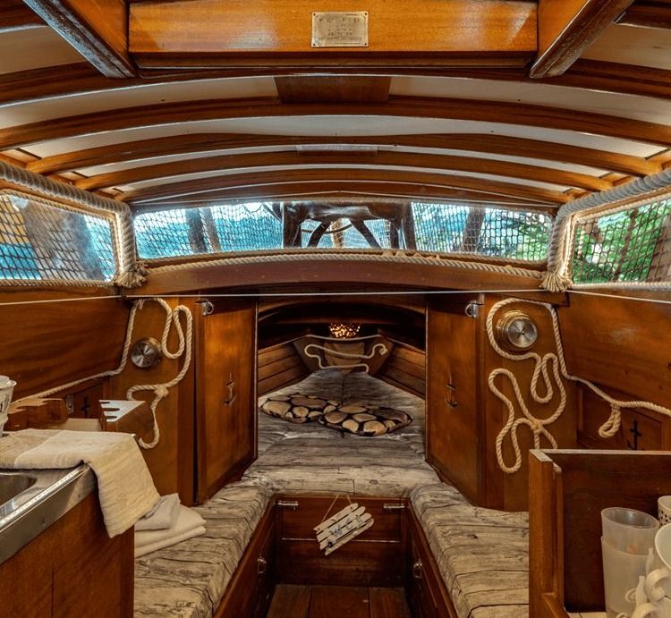 Classic wooden sailboat cabin interior with berths, portholes and rope decorations
