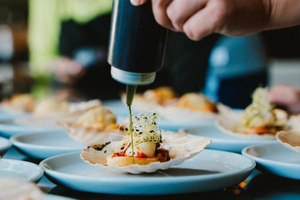 Chef drizzling sauce onto plated dishes