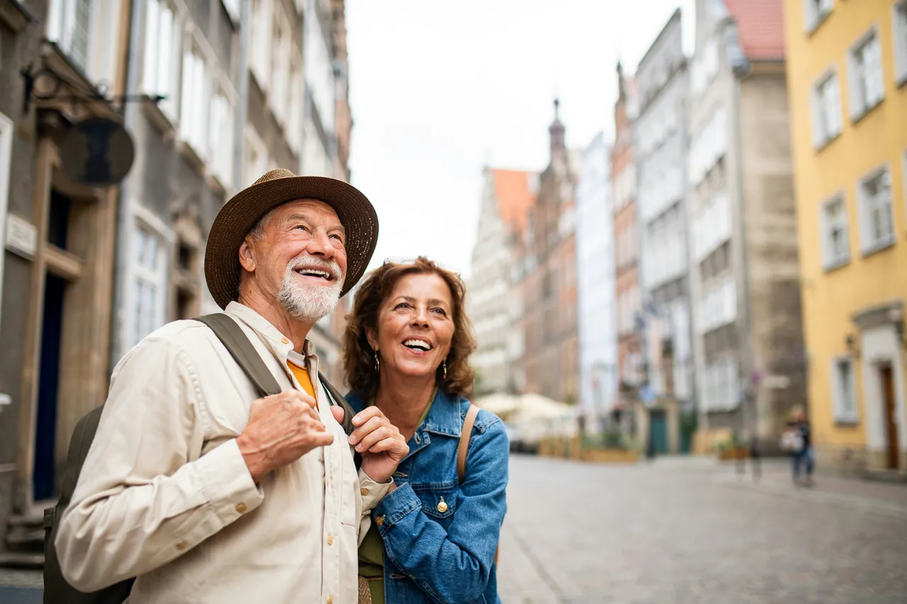  Smiling senior couple looking up while sightseeing in a European old town street