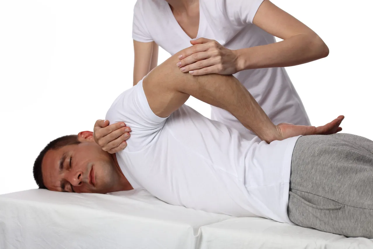 A man whose shoulder is being rotated during a Shiatsu massage.