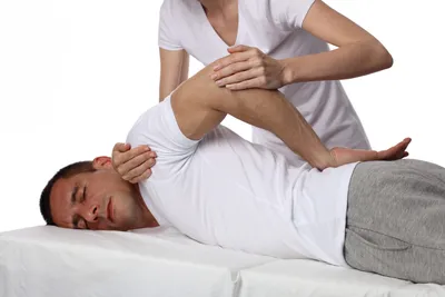 A man whose shoulder is being rotated during a Shiatsu massage.