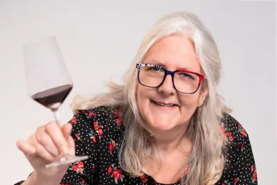 Smiling sommelier holding up a glass of red wine