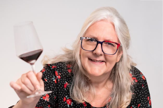 Smiling sommelier holding up a glass of red wine