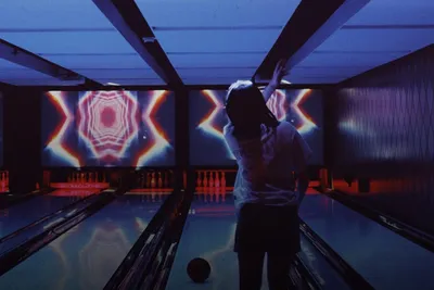 Indoor activities: person bowling in a neon-lit bowling alley