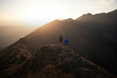 Outdoor activities: two hikers on a mountain ridge at sunset