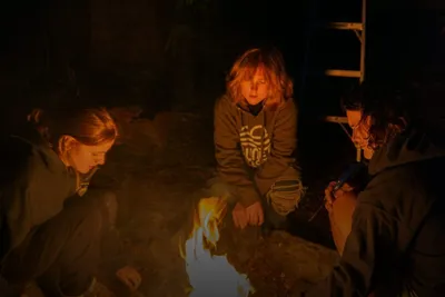Survival training: group gathered around a campfire at night