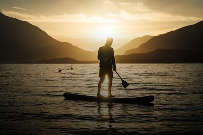 Water sports: stand-up paddleboarder on a lake at sunset