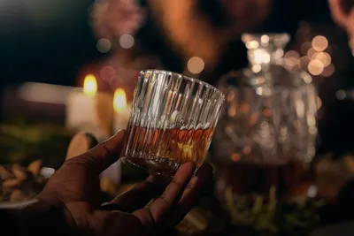 Spirits tasting: hand holding a glass of whisky by candlelight