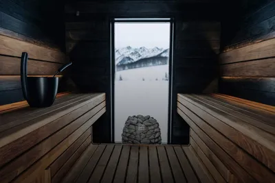 Wellness experiences: wooden sauna with a window view of snowy mountains