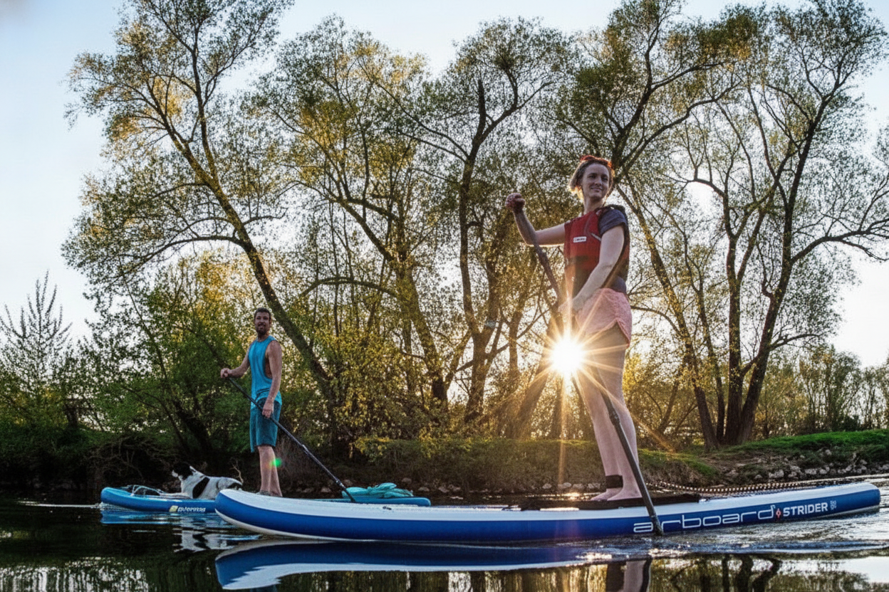 Two people on SUP boards on a lake at sunset