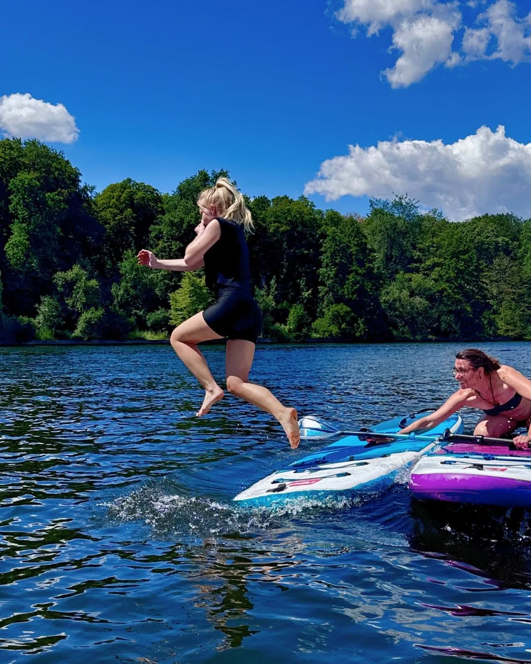 A woman jumping from a SUP board into the river