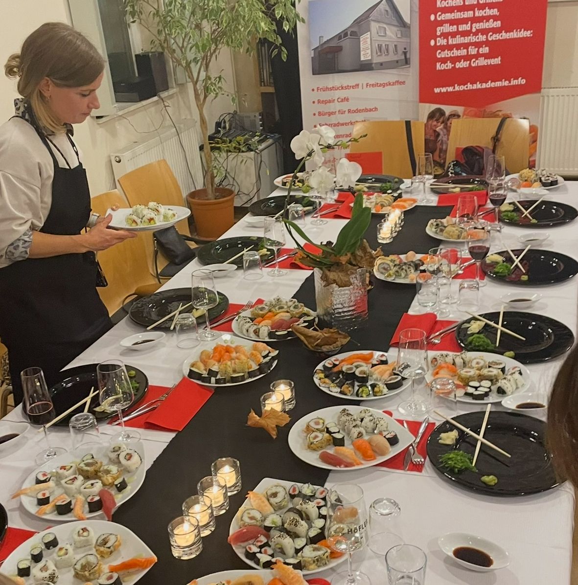 Long dinner table set with homemade sushi platters, wine glasses and candles