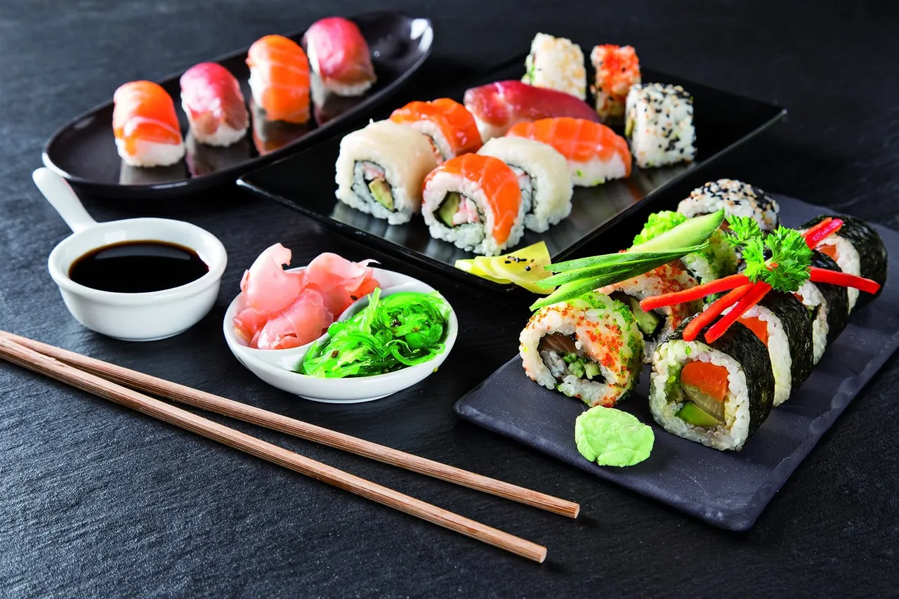 Assorted sushi with nigiri and maki rolls, soy sauce, ginger, seaweed salad and chopsticks