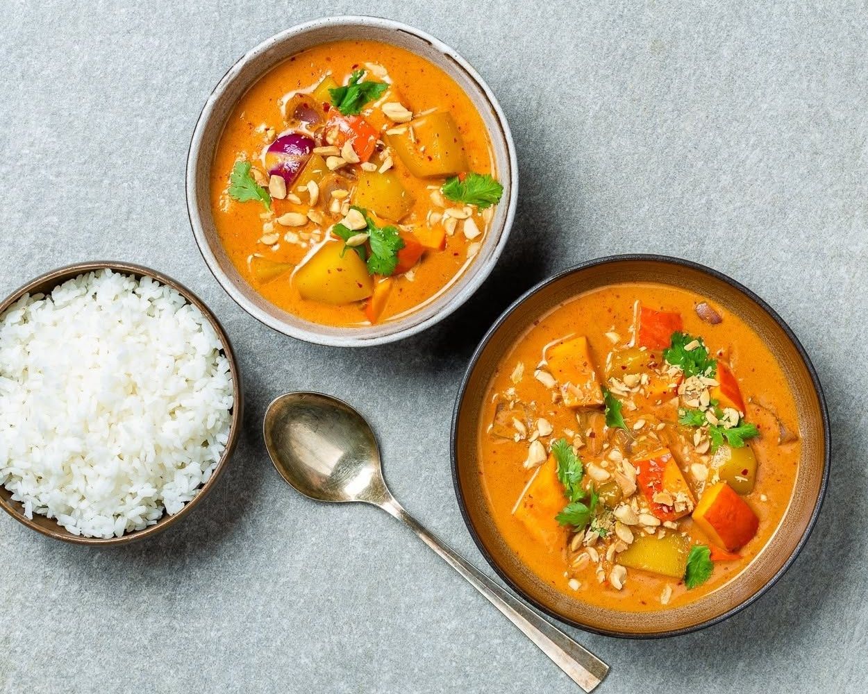 Two bowls with Thai curries and a bowl of rice
