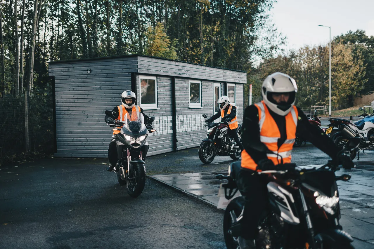 A motorcyclist rides a bike out of a a garage onto a track with several others. 