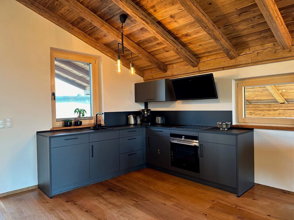 Fully equipped treehouse kitchen with dark cabinets, oven and exposed wooden roof beams