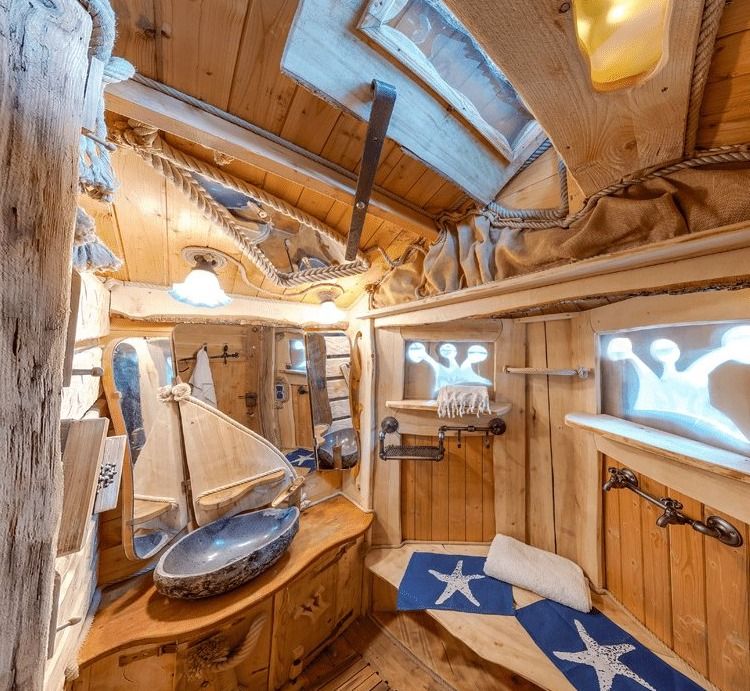 Wooden forest bathroom with stone washbasin, maritime decor and starfish bath mats