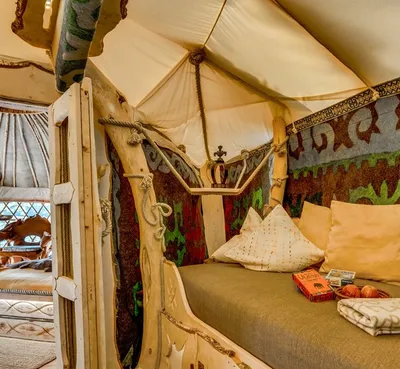 Cozy sleeping nook in a treehouse yurt with cushions, blankets and colorful felt ornaments