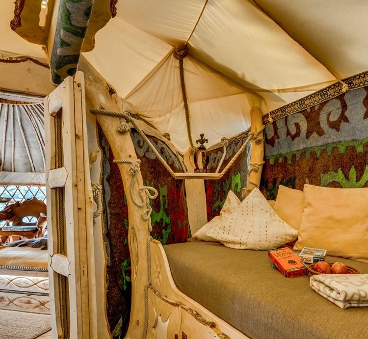 Cozy sleeping nook in a treehouse yurt with cushions, blankets and colorful felt ornaments