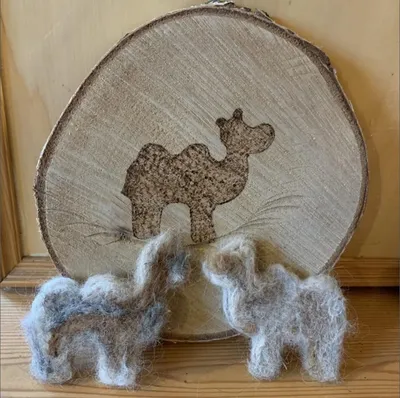 wo hand-felted alpaca figures displayed on a wooden slice
