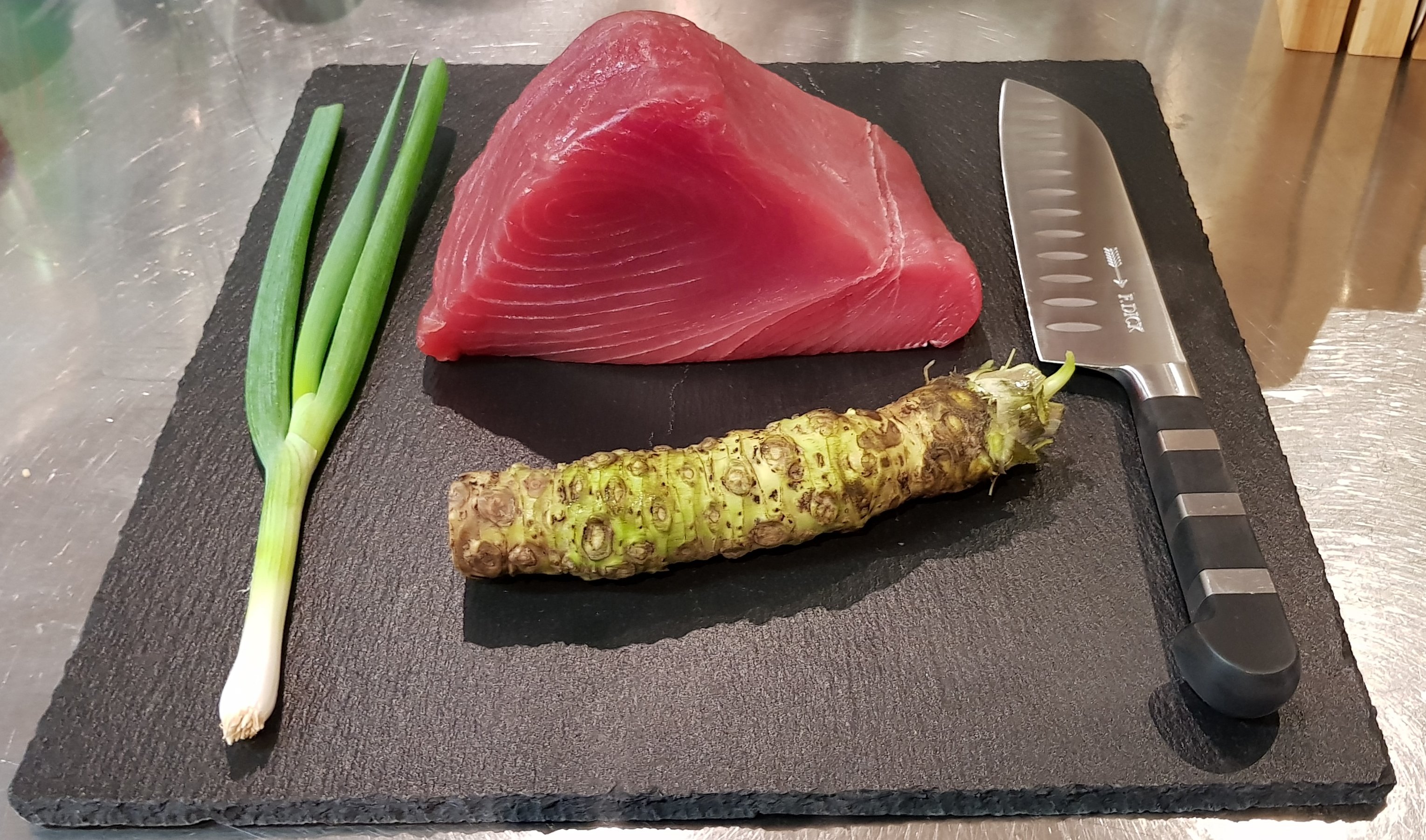 Tuna, fresh wasabi and spring onion on a dark plate