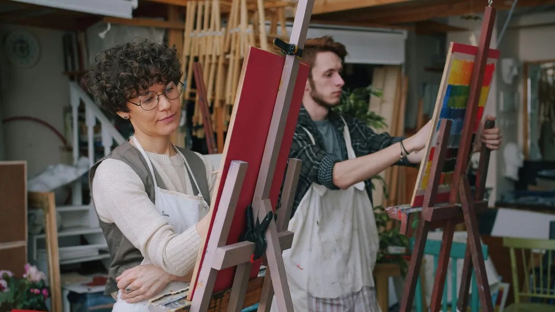 Two people painting on their own canvas