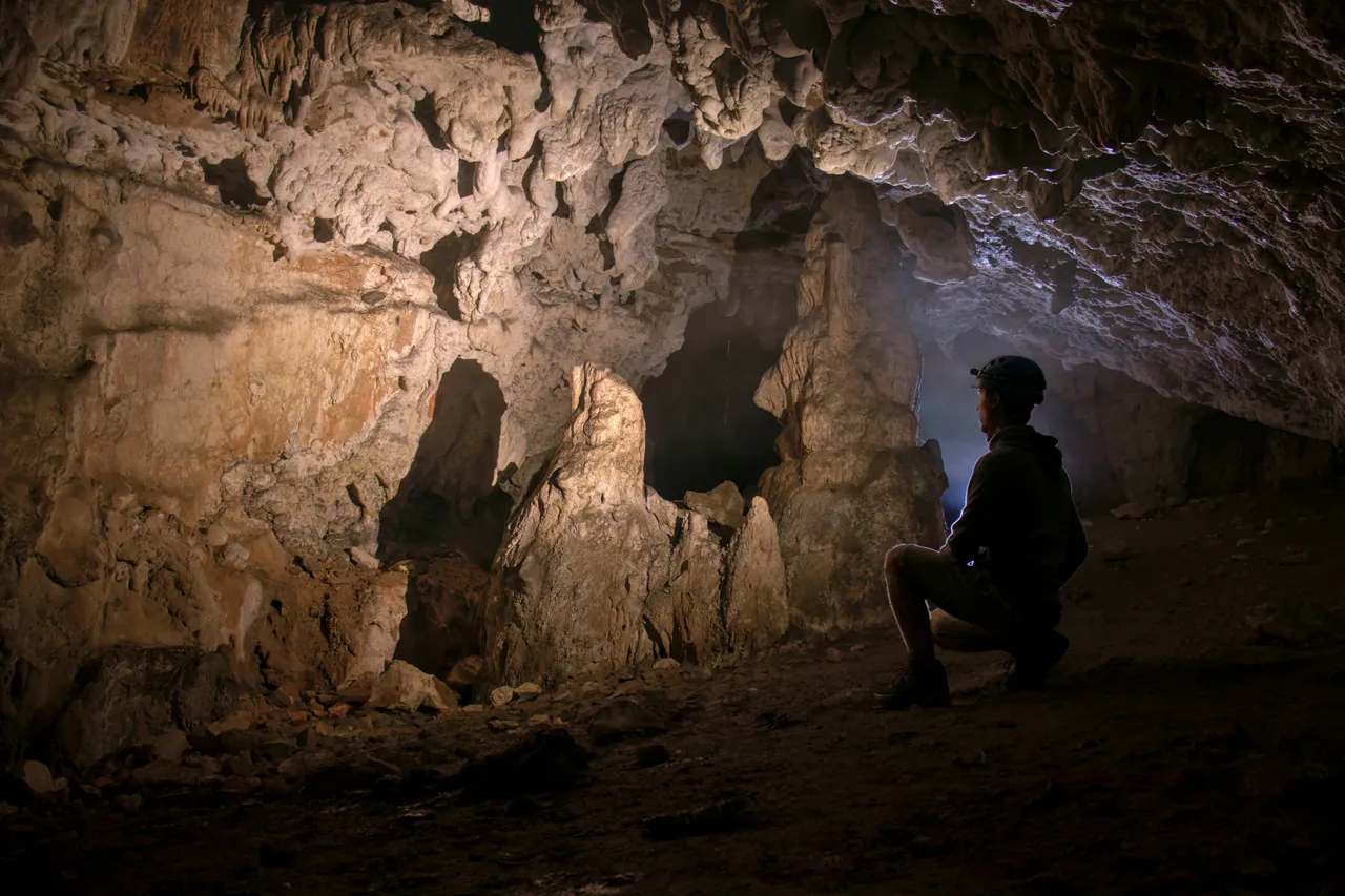 The interior of a large underground cavern featuring dramatic stalactites and rocky geological formations.