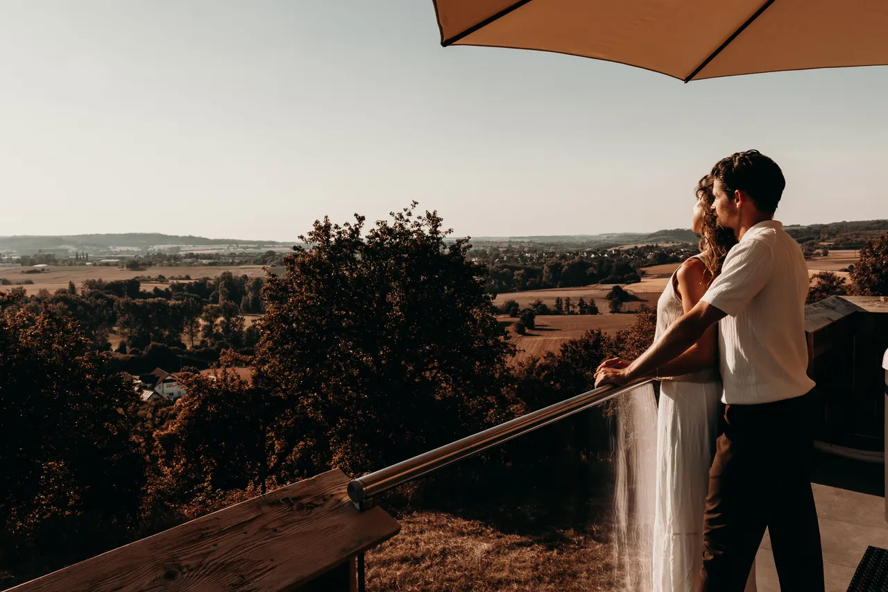 Couple on a chalet balcony enjoying the sunset view over rolling countryside