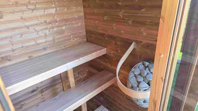 Interior of a wooden sauna with two benches and a sauna stove filled with stones