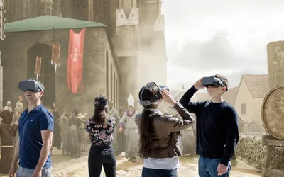 Group of visitors wearing VR headsets immersed in a medieval Vienna street scene with a monk procession