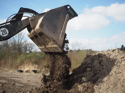 Wheel loader bucket dumping soil onto a dirt pile