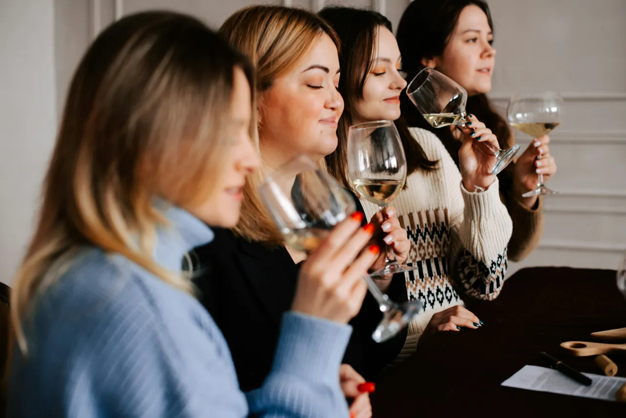 A group of women nosing wine glasses during a tasting