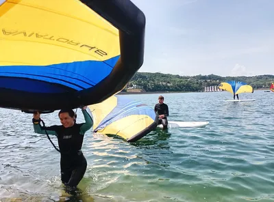 A woman carrying a hydrofoil out of the water