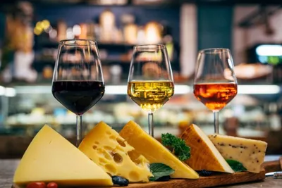 	Three glasses of red, white and rosé wine next to a platter of cheese