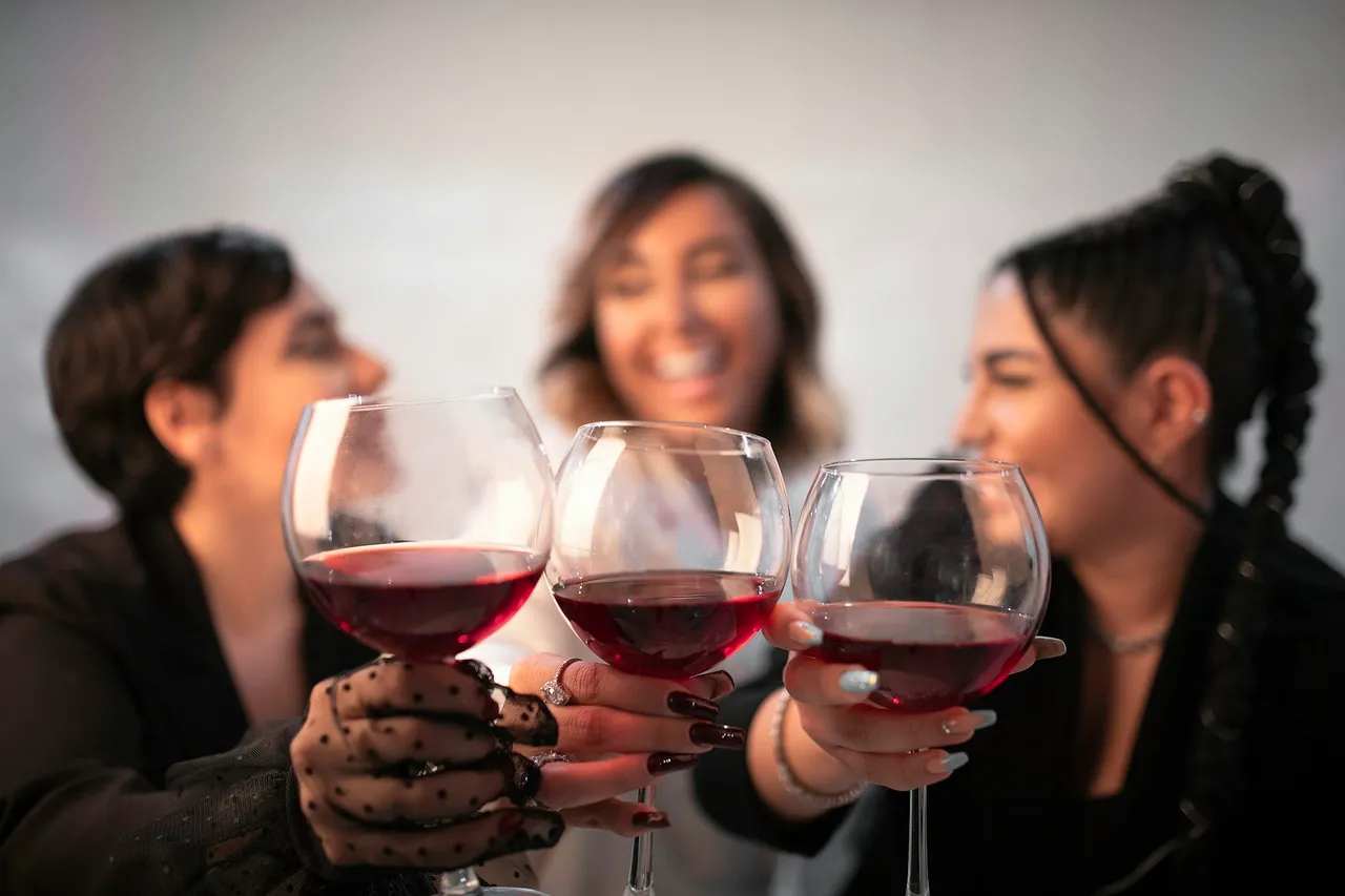 Three smiling women holding up glasses of red wine