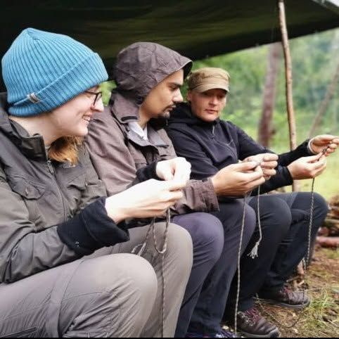 Three participants sitting under a shelter or canopy