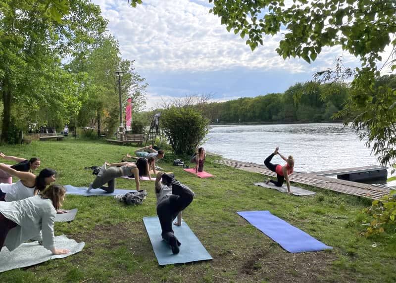 Outdoor yoga class on a riverside meadow by the Spree in Berlin
