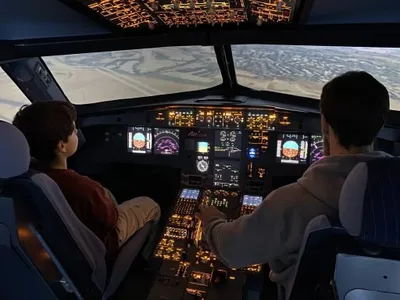 Two people sitting in an original cockpit of a A320 flight simulator
